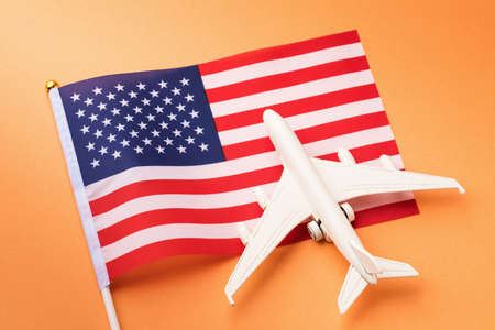 United states of america flag and toy plane on orange background, America travel conceptの写真素材