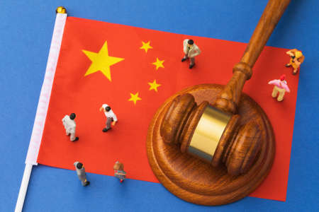 Judicial hammer, flag of China and plastic toy men on blue background, concept of litigation in Chinese societyの写真素材