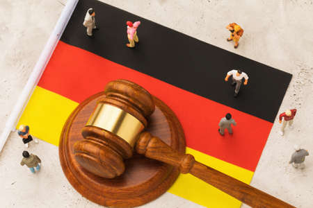 Judicial hammer, flag of Germany and plastic toy men on abstract background, concept of trial in german societyの写真素材