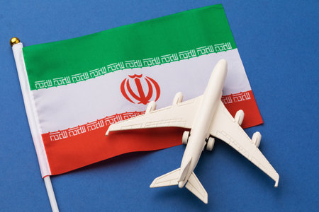 Iran flag and a toy plane on a blue background, concept on the theme of travel to the Iranian state