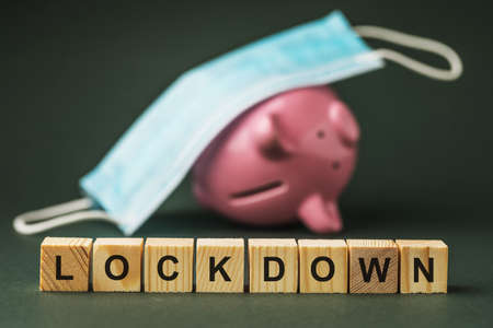 Wooden cubes with text on the background of a medical mask and an inverted piggy bank, a concept on...