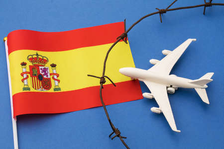 Toy plane, Spanish flag and barbed wire on blue background, Spain air border violation conceptの写真素材