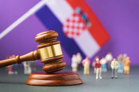 Judge gavel against the background of the blurred Croatian flag and plastic toy men, the concept of litigation in Croatian societyの写真素材