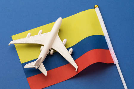 Colombian flag and toy plane on a blue background, concept of flight to Colombia, top viewの写真素材