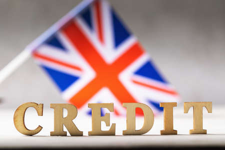 Wooden letters text and british flag on abstract background, credit concept from england
