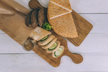 Several types of bread with lettuce and cucumbers on the kitchen boards on the tableの写真素材