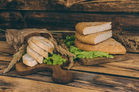 Fresh bread with lettuce in paper packaging, on a fired wooden tableの写真素材