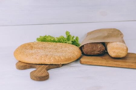 Pellet of bread baguettes with herbs on a cutting board on a white tableの写真素材