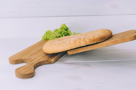 Pellet of bread with greens on a cutting board on a white tableの写真素材