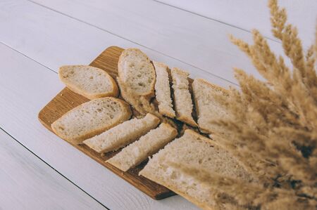 Fresh sliced bread on the kitchen board, on a light wooden tableの写真素材