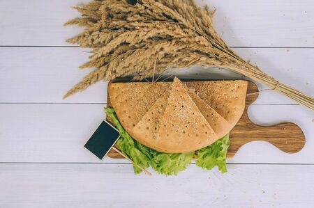 Tortilla bread with greens sliced on a cutting board on a white tableの写真素材