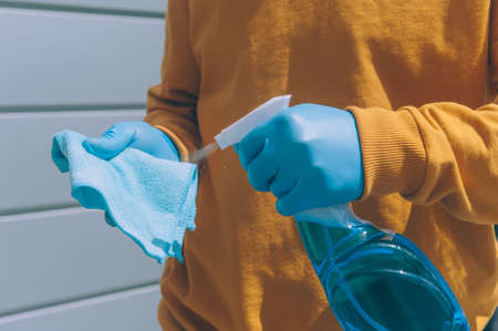 A young man disinfects a railing with a blue antiseptic and a rag in his hand. Protection and prevention from COVID-19の写真素材