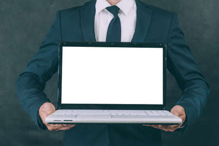 Businessman with jacket on a dark background with a laptop in his hands
