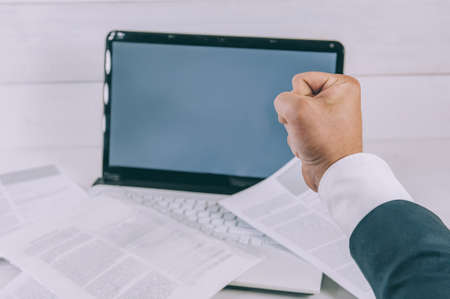 Businessman on a background of a laptop with documents on a white tableの写真素材