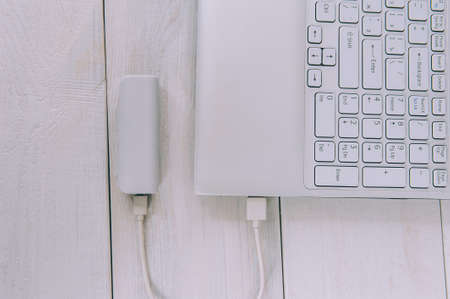 Laptop charges a portable charger on a wooden backgroundの写真素材