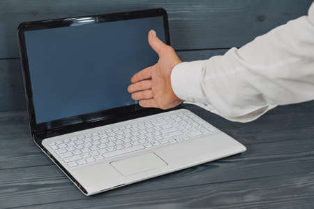 Businessman with a blue jacket on a gray background with a laptop in his handsの写真素材