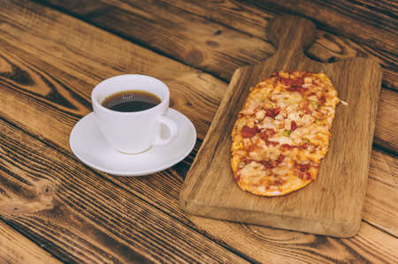 Little pizza on a wooden table with a cup of coffee. Fast food cooked at homeの写真素材