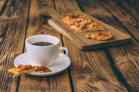Little pizza on a wooden table with a cup of coffee. Fast food cooked at homeの写真素材