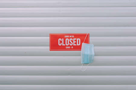 Red plate Sorry We're Closed COVID-19 with medical mask hanging on the doorの写真素材