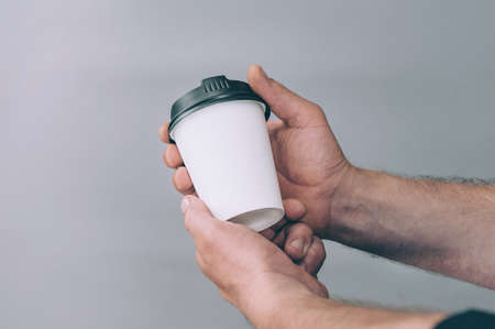 Mock-up for logos and design. A man holds in his hand a glass of coffeeの写真素材