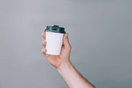 Mock-up for logos and design. A man holds in his hand a glass of coffee