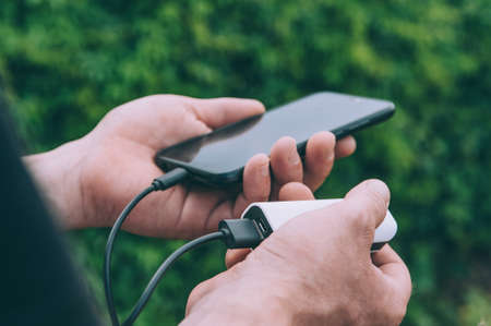 The guy charges a smartphone through a portable chargerの写真素材