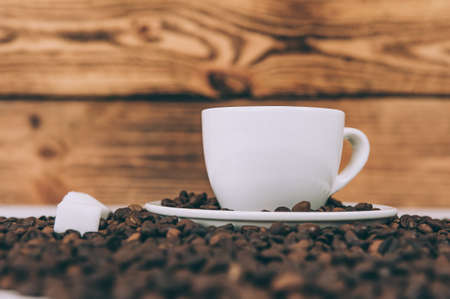 Cup for a drink with sugar on the background of coffee beans