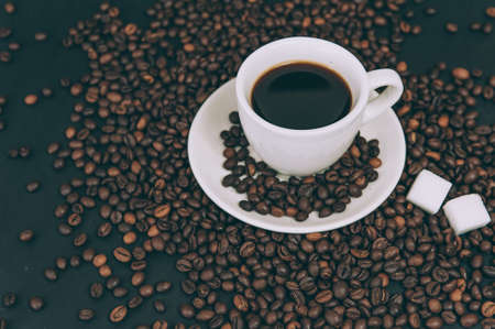Cup for a drink with sugar on the background of coffee beansの写真素材
