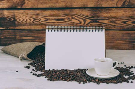 White notebook on a background of a cup and coffee beansの写真素材