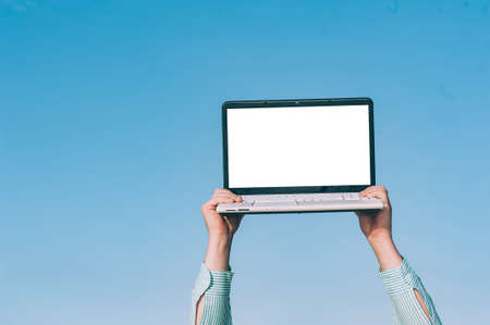 Mock up laptop in the hands of a man, against the skyの写真素材