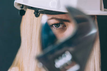 Woman in a construction helmet on her head and a metal key in her handsの写真素材