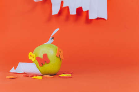 Concept Back to School. Green apple with colored letters on an orange backgroundの写真素材