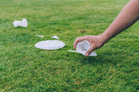 Man cleans plastic trash from nature on a background of green grass