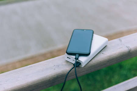 Portable charger charges a smartphone against the backdrop of natureの写真素材