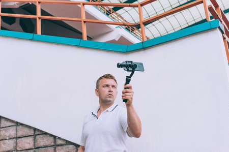 Blogger in the stadium shoots video on a smartphone with a manual camera stabilizer
