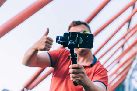 Blogger in the stadium shoots video on a smartphone with a manual camera stabilizerの写真素材