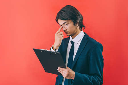 Businessman with a folder for documents in hands, on a red backgroundの写真素材