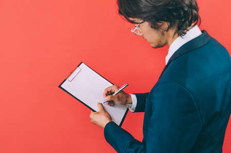 Businessman with a folder for documents in hands, on a red background