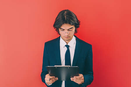 Businessman with a folder for documents in hands, on a red backgroundの写真素材