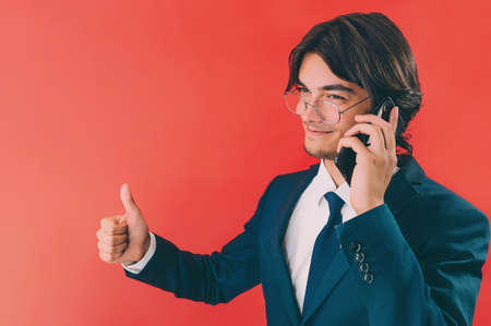 Businessman with a smartphone in his hands, on a red backgroundの写真素材
