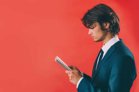 Businessman with a mock up notepad in his hands on a red background