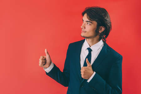 Businessman shows thumbs up over red backgroundの写真素材