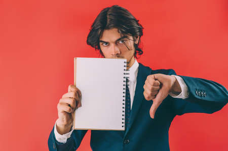Businessman with a mock up notepad in his hands on a red backgroundの写真素材