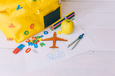 Back to school concept. Yellow backpack with office supplies on a wooden background