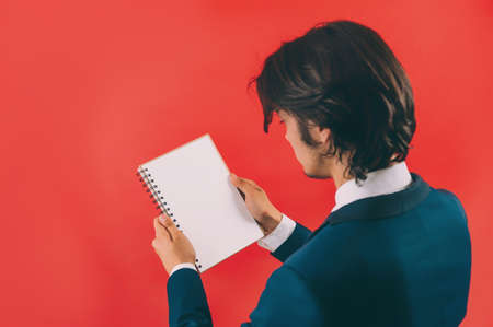 Businessman with a mock up notepad in his hands on a red backgroundの写真素材