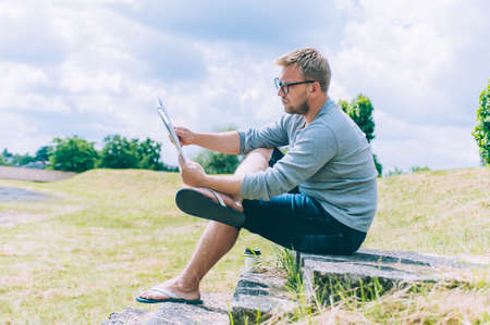 The guy with a cup of coffee reads a book outdoorsの写真素材