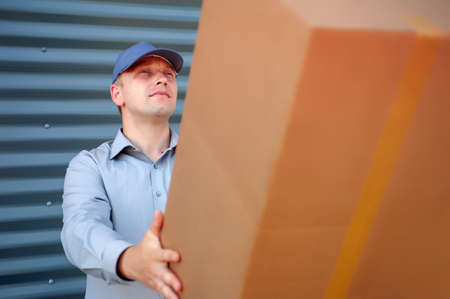 A man in a gray suit in his hands with a cardboard box. Concept on the topic of postal delivery
