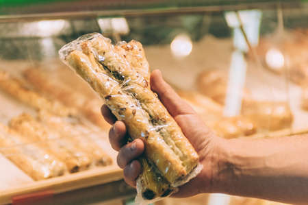 A man holds fresh baked goods in his hands in a supermarketの写真素材