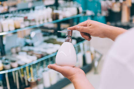 A man holds a bottle for liquid soap in his hands. Concept man chooses a product in a storeの写真素材