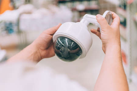 A man holds a street video camera in his hands. Concept man chooses a product in a store
